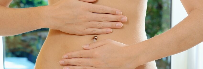 Hier sieht man den nackten Bauch einer Frau, die ihre Handflächen darauf legt.