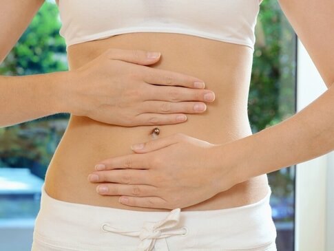 Hier sehen Sie eine Frau, welche sich mit beiden Händen über den Bauch streicht. 