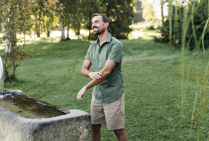 Mann steht vor einer Tröge mit Kneipp-Wasser