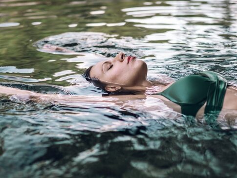 Eine Frau in Bikini lässt sich im wohltuenden Heilwasser treiben.