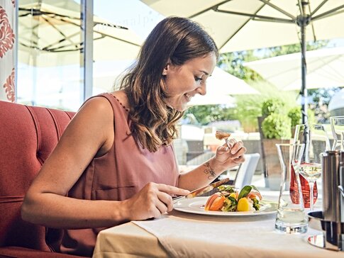 Hier sehen Sie eine Frau mit rosa Oberteil, die eine gesunde Mahlzeit genießt.