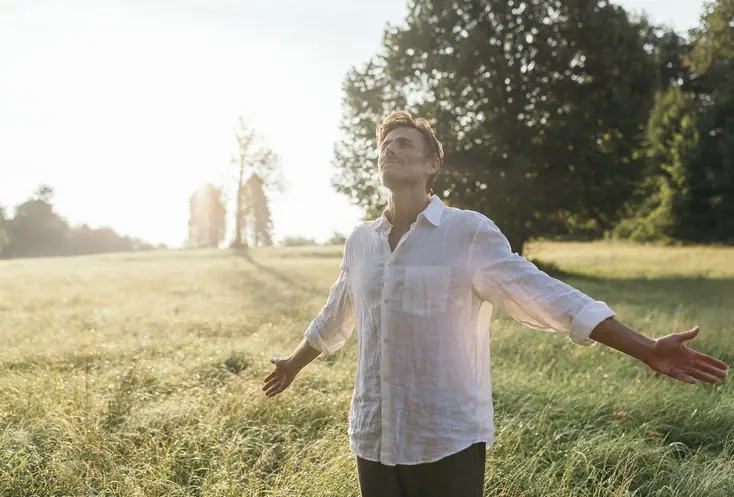 Mann steht in der Morgensonne in einem Feld