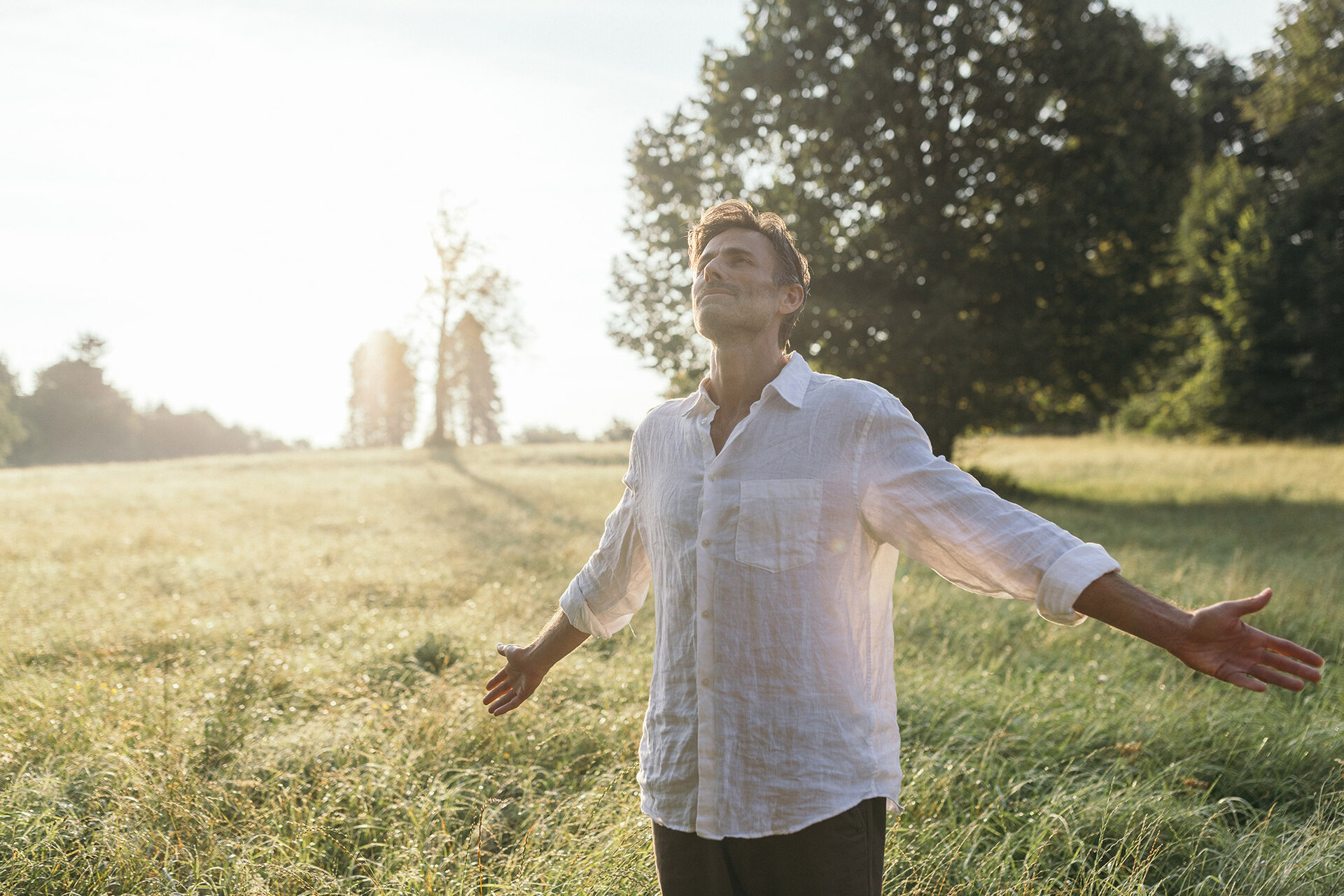 Mann steht in der Morgensonne in einem Feld