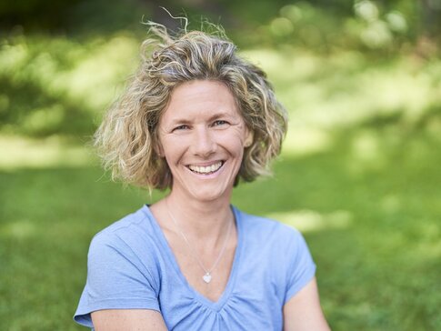 Hier sehen Sie eine blonde Frau mit einem blauen T-Shirt. 