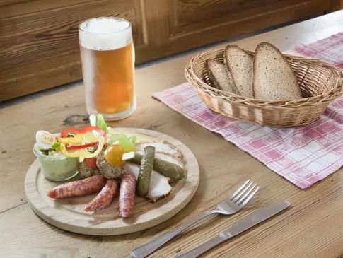 Hier sehen Sie einen Bortzeitteller mit Wurst, Bauernbrot, Käse und ein Bier.