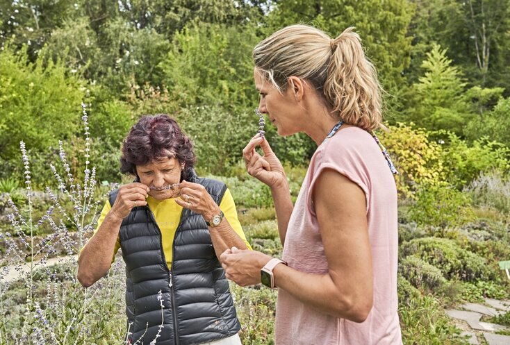 Zwei Damen riechen an einem Stück Lavendel.