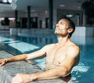 Ein Mann genießt die Sonne, während er im Thermalwasser steht.