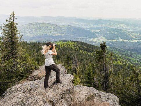 Junge Frau mit Fernglas am Berg