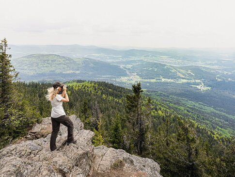 Junge Frau schaut mit Fernglas ins Tal