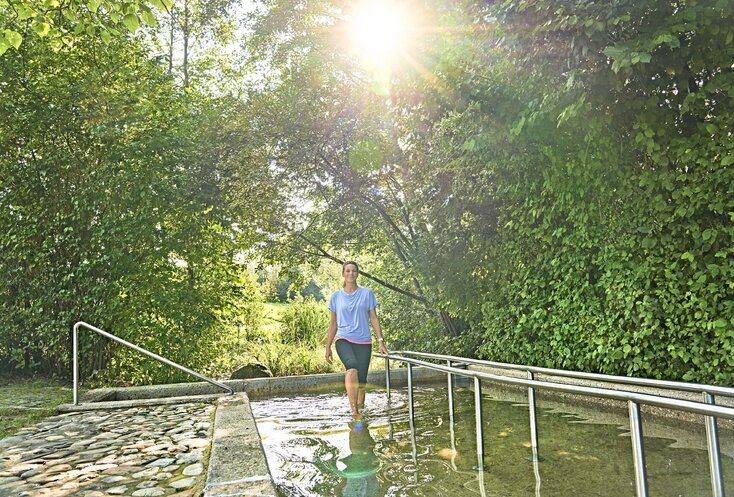 Hier sehen Sie eine Frau, die durch ein Becken mit klarem Wasser watet.