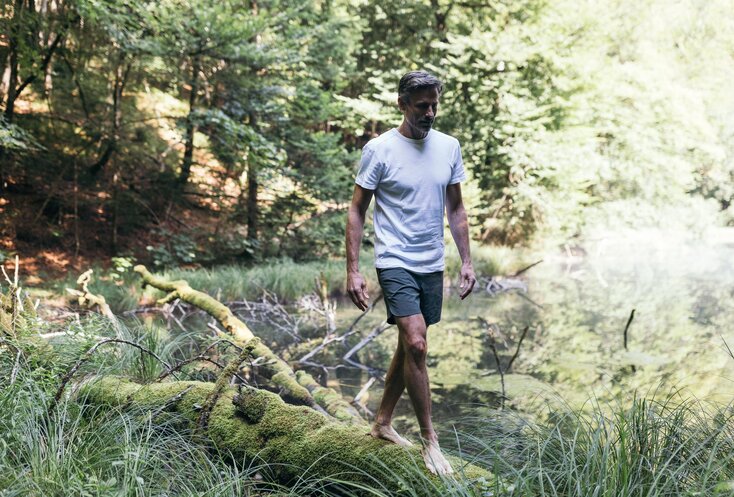 Mann balanciert auf Stamm neben See im Wald
