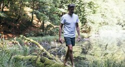 Mann balanciert auf Stamm neben See im Wald