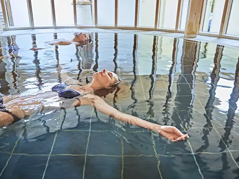 Hier sehen Sie eine Frau in blauem Bikini in einem Schwimmbecken schweben. 