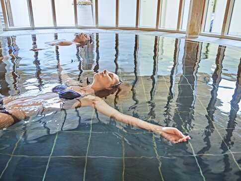 Hier sehen Sie eine Frau in blauem Bikini in einem Schwimmbecken schweben. 