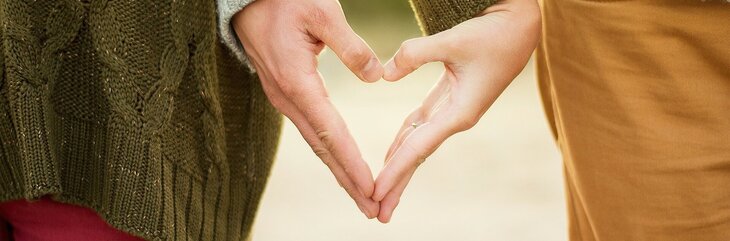 Hier sehen Sie wie zwei Personen mit ihren Händen ein Herz formen. 