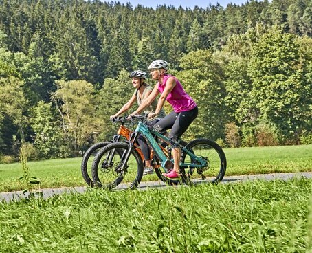 Hier sehen Sie zwei Frauen auf E-Bikes fahren.