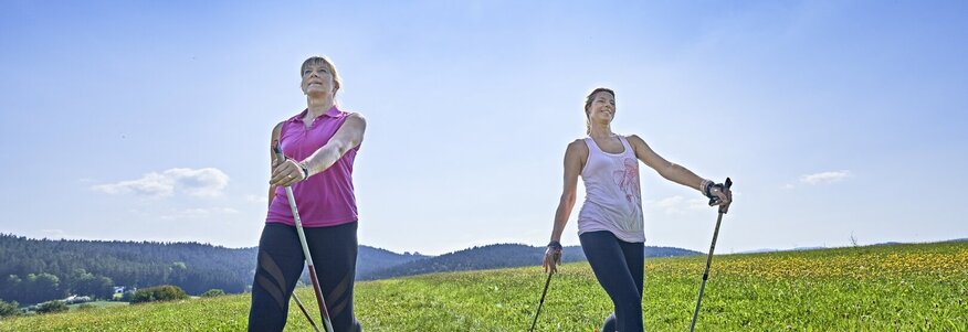 Zwei Frauen beim Nordic Walking im Sonnenschein