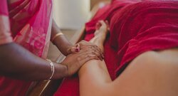 Eine indische Therapeutin führt eine ayurvedische Anwendung an einer Patientin durch