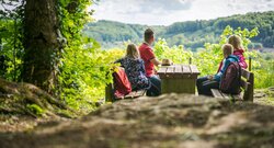 Familie schaut bei der Wanderrast in die Ferne.